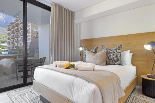ein Schlafzimmer mit einem großen weißen Bett und einem Balkon in der Unterkunft The Cedar Unit 101 in Kapstadt