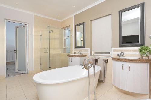 a bathroom with a tub and a shower and a sink at Pinnacle Point Heritage Villa in Mossel Bay