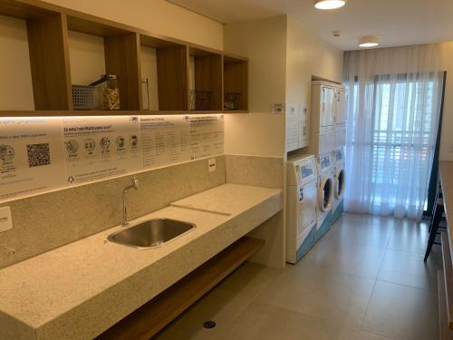 a kitchen with a sink and a washer and dryer at Studio Metrô Brooklin in Sao Paulo