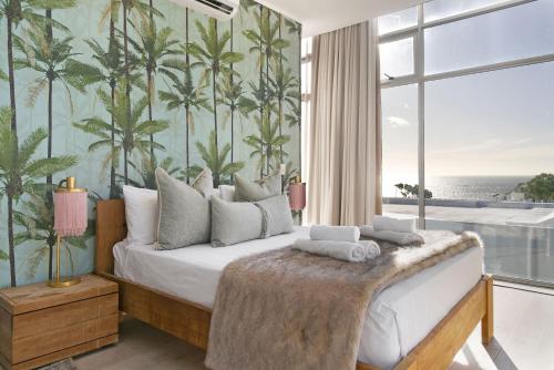 a bedroom with a bed with a palm tree wallpaper at The Grange 11 in Cape Town