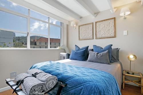 a bedroom with a bed with blue pillows and a window at Studio on Hope by HostAgents in Cape Town