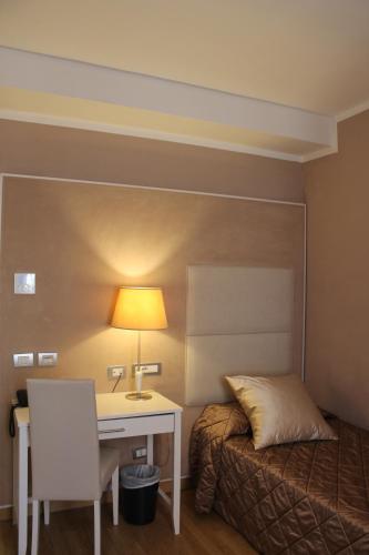 a bedroom with a bed and a desk with a lamp at Hotel Centrale in Olbia