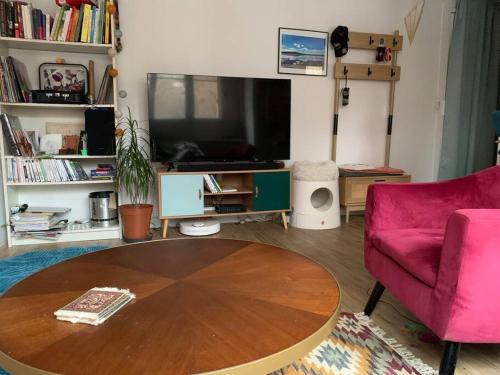 Appartement calme - Parking - Métro في إيفري سور سين: غرفة معيشة مع طاولة وأريكة وردية