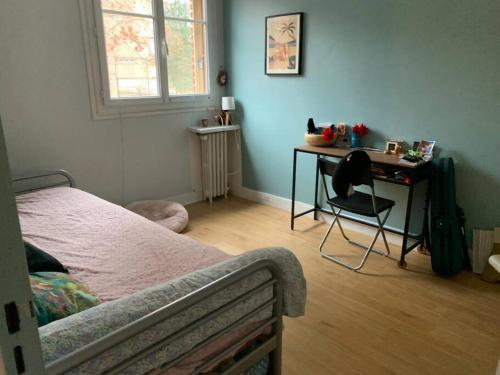 une chambre avec un lit et un bureau avec une chaise dans l'établissement Appartement calme - Parking - Métro, à Ivry-sur-Seine