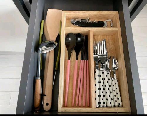 a wooden drawer with utensils in a kitchen at Feel at Home Dongseongno Star BnB in Daegu