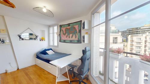 Kleines Zimmer mit einem Schreibtisch und einem Fenster in der Unterkunft Boho studio near the Eiffel Tower in Paris