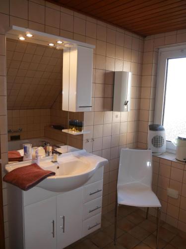 a bathroom with a sink and a mirror and a chair at Ferienhaus Baarsen 30 in Bad Pyrmont