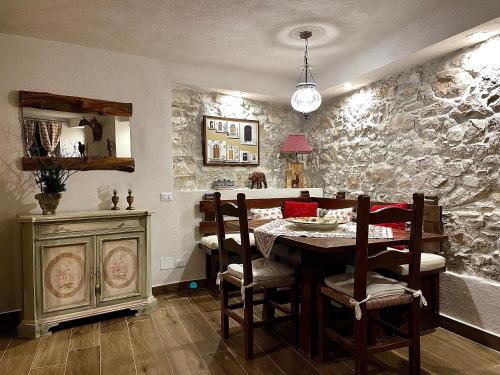 d'une salle à manger avec une table et un mur en pierre. dans l'établissement PESCULUM nel borgo, à Pescocostanzo