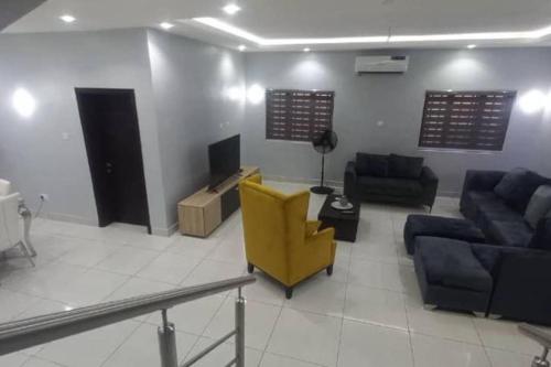 a living room with a yellow chair and a couch at Luxe Living:4Bed, TV, Pool& WiFi in Lekki