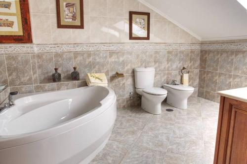 a bathroom with a white tub and a toilet at Camino de las Mimosas: relax en un entorno idílico in Folgueras