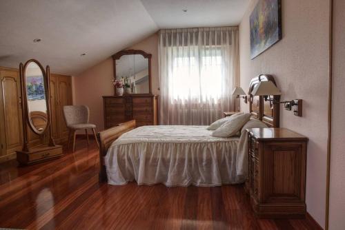 a bedroom with a bed and a dresser and a mirror at Camino de las Mimosas: relax en un entorno idílico in Folgueras