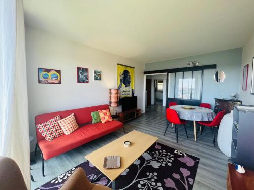 een woonkamer met een rode bank en een tafel bij Le Rétro - Splendide appartement in Poitiers