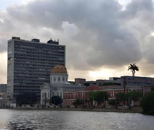 a building with a dome on top next to a body of water at Aconchegante, ótima localização e vista para o mar in Recife