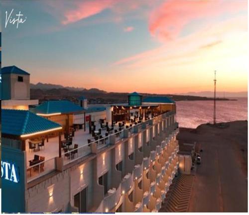 a hotel with a view of the ocean at sunset at Vista Haql Hotel in Al Humaizah