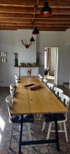 De Bossenaarshoeve في Maarkedal: طاولة خشبية كبيرة مع كراسي بيضاء في الغرفة