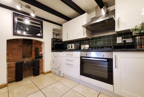 a kitchen with white cabinets and a stove top oven at Shrewsbury 3 Bedroom Abbey Foregate in Shrewsbury