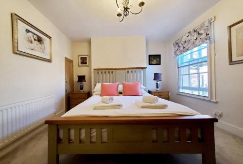 Schlafzimmer mit einem Bett mit rosa Kissen und einem Fenster in der Unterkunft Shrewsbury 3 Bedroom Abbey Foregate in Shrewsbury