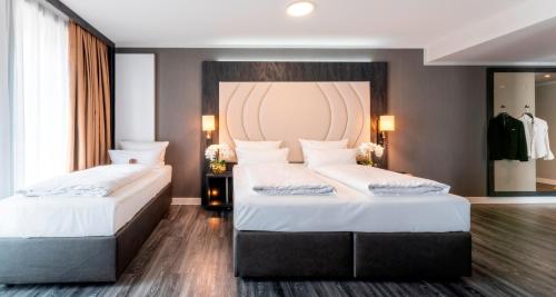 a bedroom with two beds with white sheets and a headboard at PLAZA Premium Heidelberg in Heidelberg