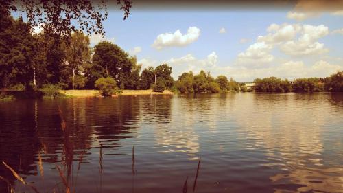 a large body of water with trees and clouds at Obytný kontejner in Roudná
