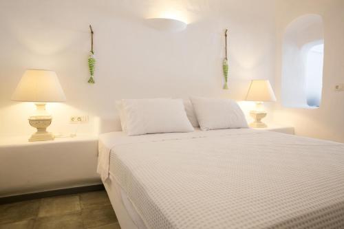 カルテラドスにあるIl Melograno Traditional Cave Houseの白いベッドルーム(ベッド1台、ランプ2つ付)