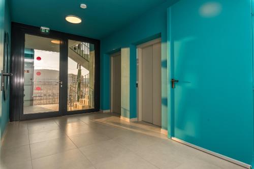 an empty hallway with blue walls and glass doors at Waterfront City River view in Budapest