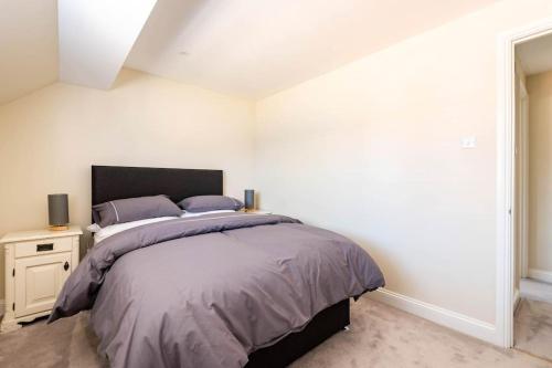 a bedroom with a large bed and a white wall at Central Village Cottage, The Corders in Moreton in Marsh