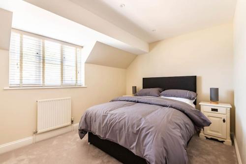 a bedroom with a large bed and a window at Central Village Cottage, The Corders in Moreton in Marsh