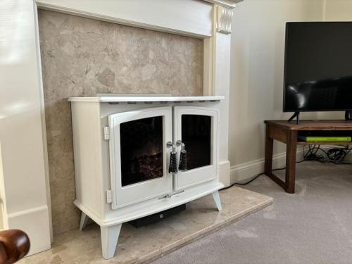 a white entertainment center with a tv and a table at Central Village Cottage, The Corders in Moreton in Marsh