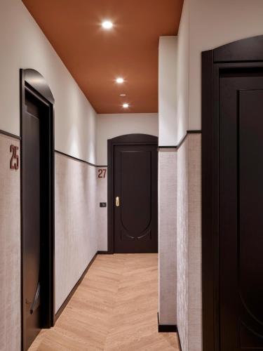 a hallway with black doors and wood floors and a corridorngthngthngthngthngth at Hotel Antica Fonte in Brescia