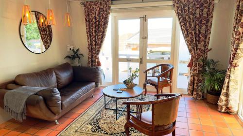 a living room with a leather couch and a table at Plattekloof Premium Lodge in Plattekloof