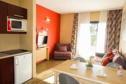 a kitchen and living room with an orange wall at Comfort Aparthotel Marseille Prado in Marseille