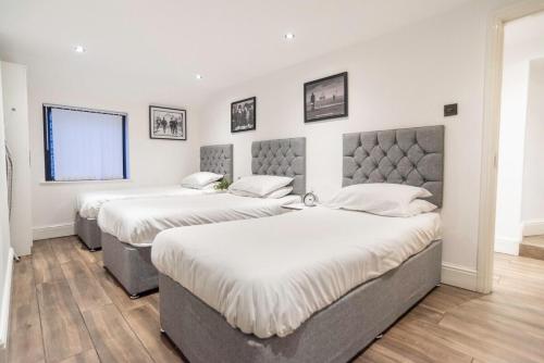 two beds in a room with white walls and wood floors at Camden Apartments 2 in Liverpool
