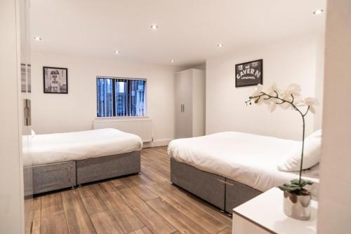 Habitación con 2 camas, paredes blancas y suelo de madera. en Camden Apartments 2, en Liverpool