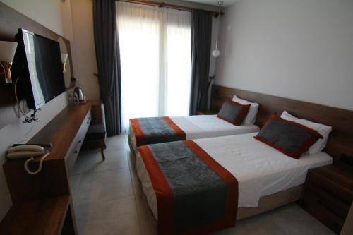 a hotel room with a bed and a television at Ornella Butik Otel in Edremit