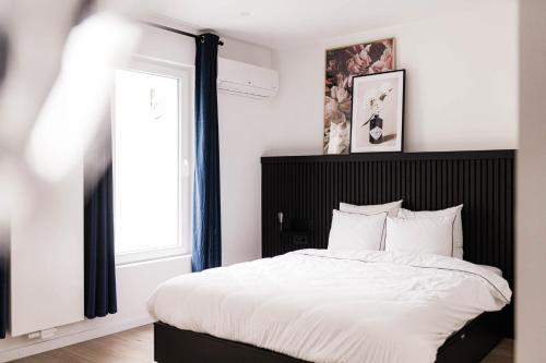um quarto com uma cama com uma cabeceira preta e uma janela em Gorgeous getaway in the old city centre of Antwerp em Antuérpia