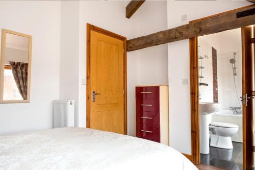 a bedroom with a bed and a bathroom at Poppy Cottage - Great Houndbeare Farm Holiday Cottages in Aylesbeare