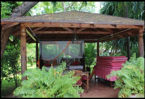 een houten paviljoen met een tafel en stoelen in een tuin bij Ornella House Resort: Spacious 5-Bed Villa in Tropical Malindi in Malindi