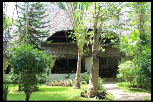 een gebouw met een grasdak met bomen ervoor bij Ornella House Resort: Spacious 5-Bed Villa in Tropical Malindi in Malindi