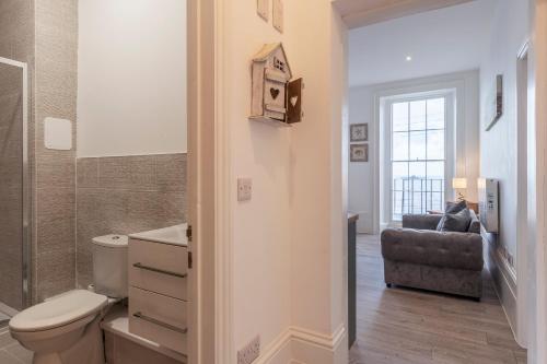 a bathroom with a toilet and a chair at Seaside Serenity: Stylish Sea View Apartments in Herne Bay in Kent