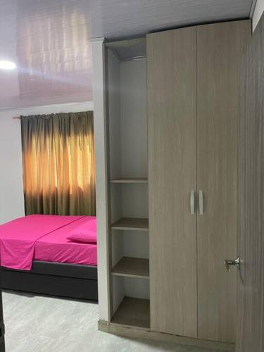 een slaapkamer met een bed en een kast met roze lakens bij Hostal el ebenezeer in Santa Marta