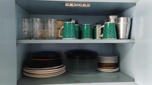 a pantry with plates and cups on a shelf at Moka Refúgium-Casa de praia aconchegante e espaçosa in Belém