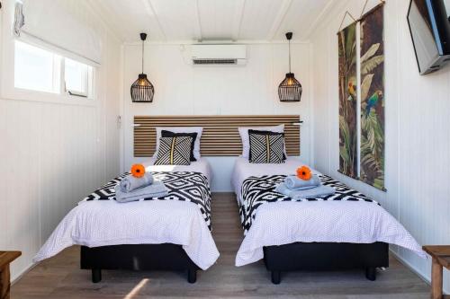 2 camas en una habitación con paredes blancas en Cabana incl boat, jacuzzi,subboarts on a quiet park with private parking, en Loosdrecht