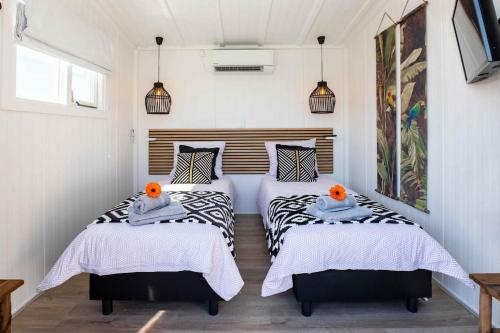 two beds in a room with white walls at Cabana incl boat, jacuzzi,subboarts on a quiet park with private parking in Loosdrecht