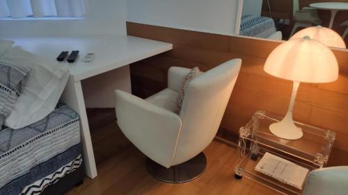 a white chair sitting next to a desk with a lamp at Cosy Studio Azores Beach in Ponta Delgada