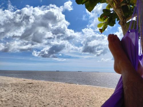 a person laying in a hammock on a beach at Moka Refúgium-Casa de praia aconchegante e espaçosa in Belém
