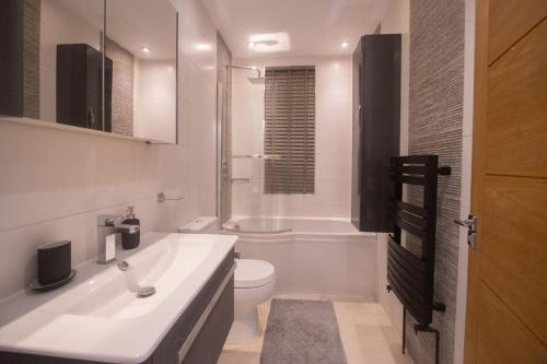 Baño blanco con lavabo y aseo en OikosHomes Three Bedroom Flat in London, en Londres