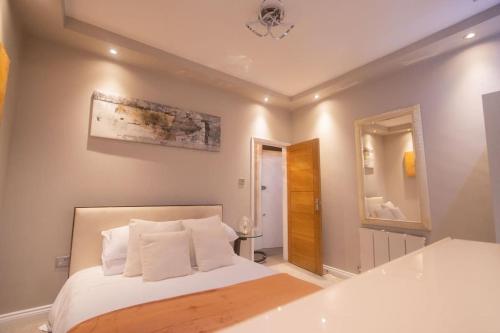 1 dormitorio con cama y espejo en OikosHomes Three Bedroom Flat in London, en Londres