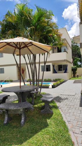 two picnic tables with an umbrella in the grass at Pipa Céu Azul in Pipa