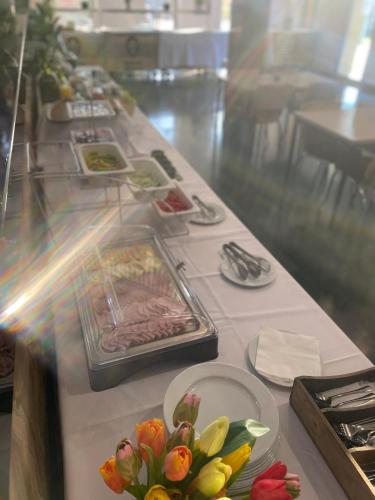 a long table with plates of food and flowers on it at Malkia Penzion in Orechová Potôň