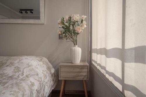um vaso com flores numa mesa ao lado de uma cama em PRO HOME NOVO em Antofagasta
